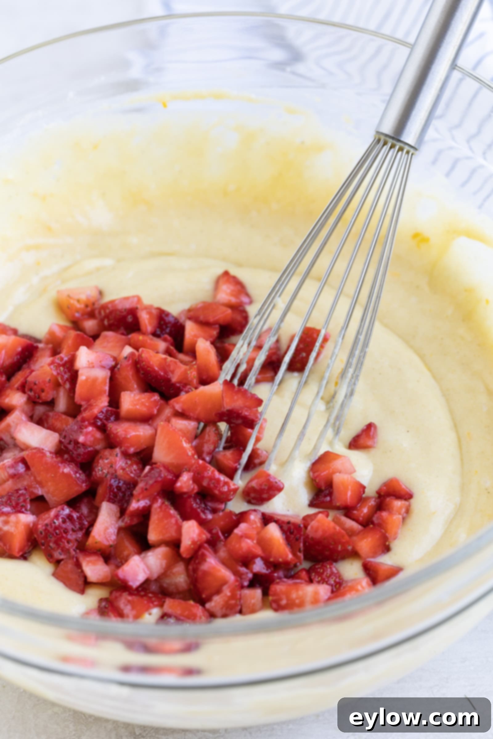 Fluffy Gluten-Free Strawberry Muffins 6 Red diced strawberries being mixed into the yellow muffin batter.