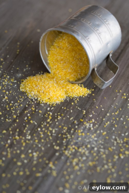Golden Cheesy Polenta with Poached Eggs 3 Coarse yellow cornmeal spilled onto a gray cutting board, ready for cooking.