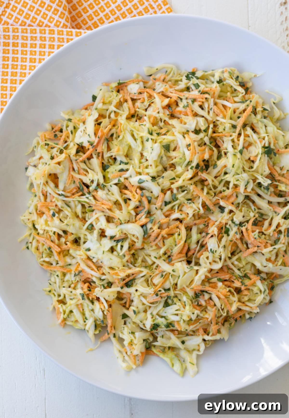 Quick and Creamy Coleslaw 2 Round white bowl of colorful coleslaw with carrots and parsley.