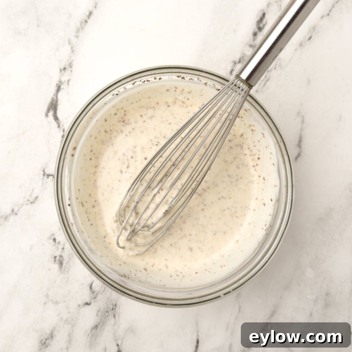 Quick and Creamy Coleslaw 8 creamy salad dressing with a silver whisk in a small glass bow.