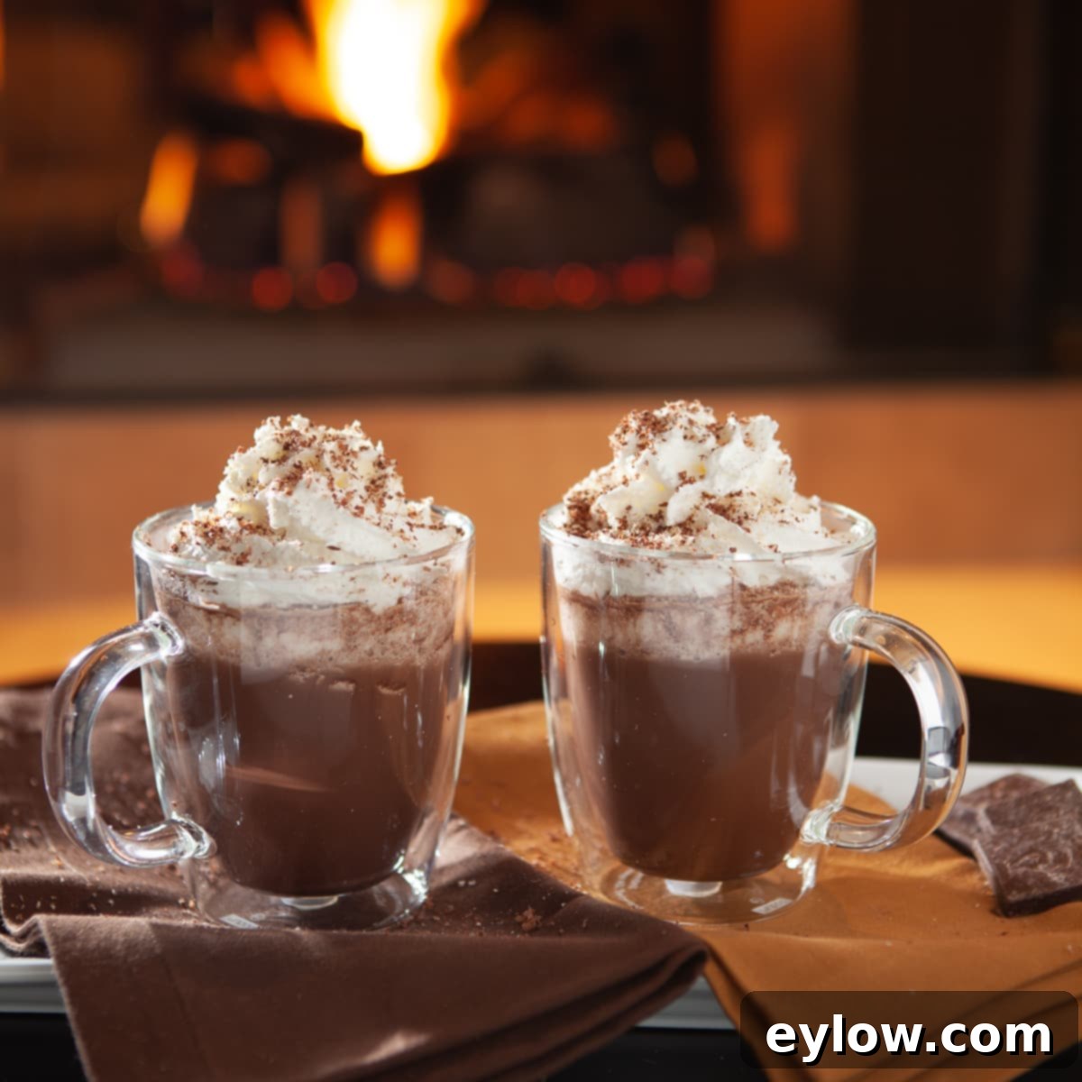 Easy Boozy Hot Chocolate 6 Hot chocolate with whipped cream topping in front of a fireplace.