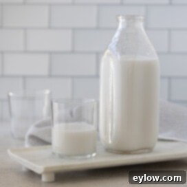 A square crop image of coconut milk in a glass bottle on a light background, symbolizing homemade freshness.