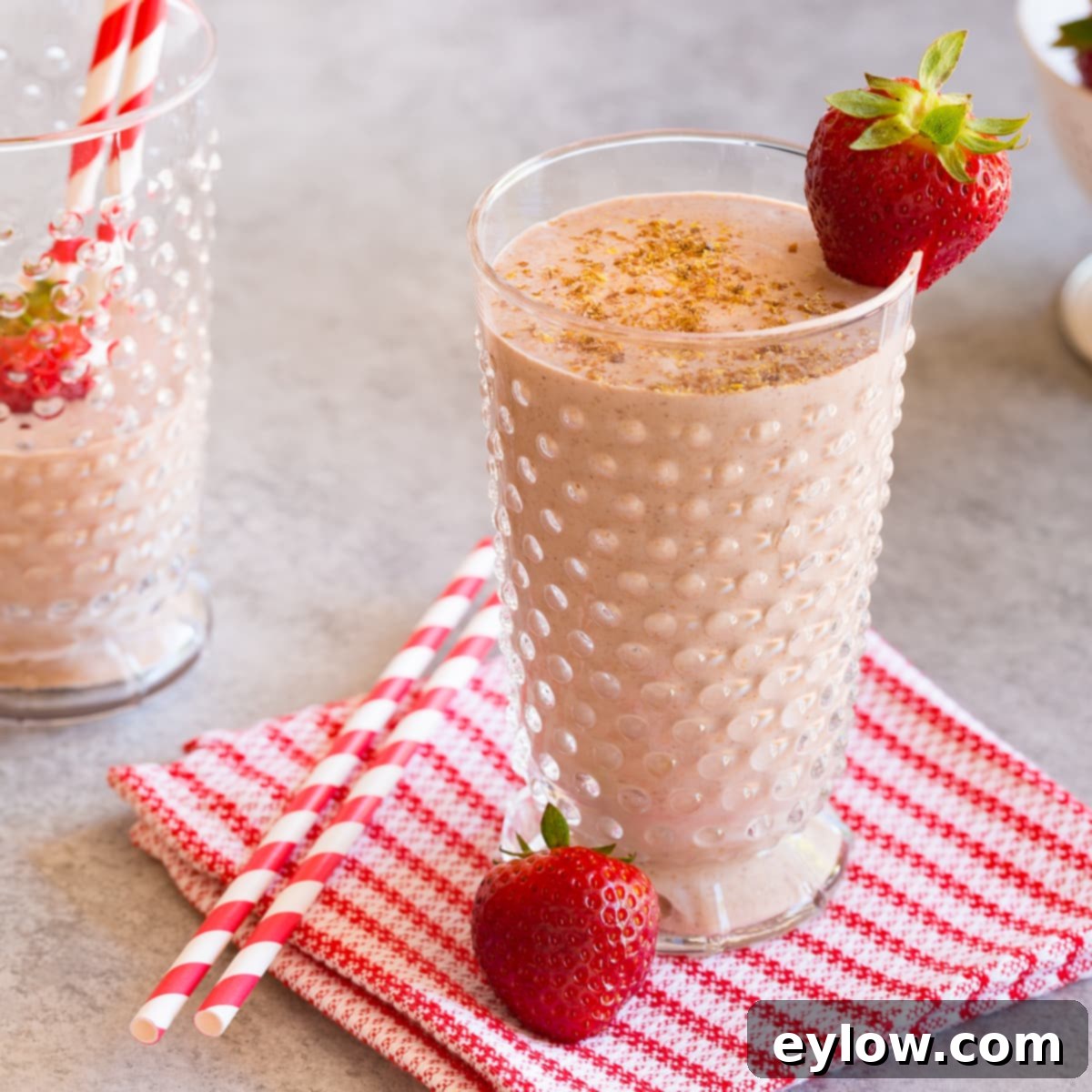 Strawberry banana smoothie in a glass with berries, a perfect use for homemade coconut milk.