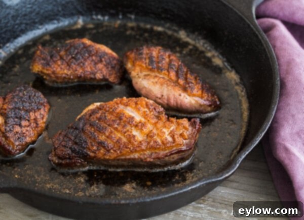 Crispy Seared Duck Breast sizzling in a hot cast iron skillet.