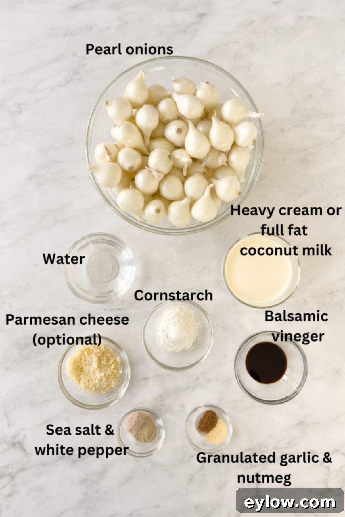 Effortless and Velvety Creamed Pearl Onions 3 All the fresh ingredients for creamed pearl onions, including pearl onions, heavy cream or coconut milk, cornstarch, balsamic vinegar, fresh thyme, salt, pepper, nutmeg, and Parmesan cheese, neatly arranged in prep bowls on a kitchen counter.