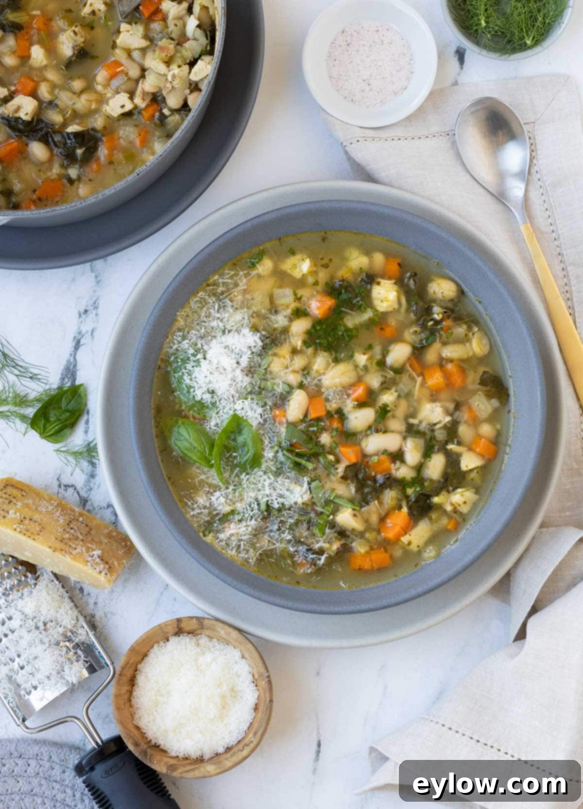 Effortless Thanksgiving Your Guide to a Calm Holiday 4 A gray bowl of white bean soup with basil, parmesan, and kale.