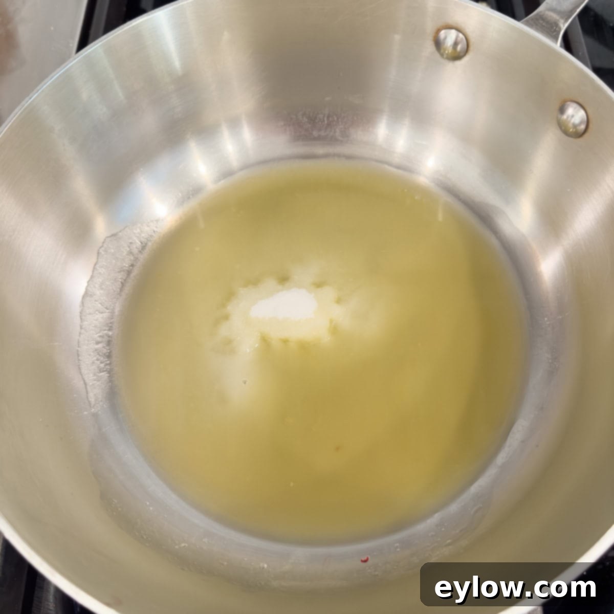 Artisan Whole Berry Cranberry Sauce 5 A stainless pan with orange juice and sugar melting, the base for healthy homemade cranberry sauce.