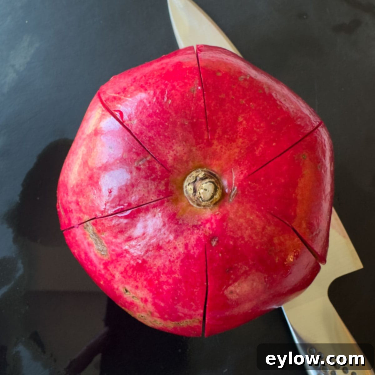 Artisan Whole Berry Cranberry Sauce 8 A whole bright red pomegranate with cuts sliced into the skin, preparing for easy seeding.