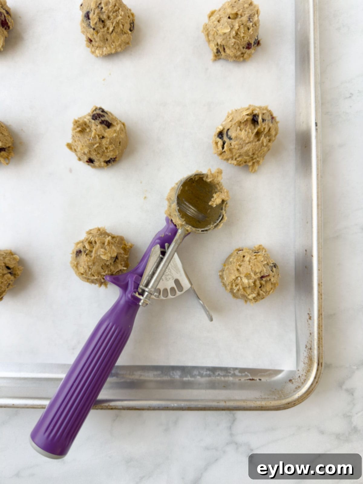 Homemade Cranberry Oatmeal Cookie Bliss 11 Balls of cranberry oatmeal cookie dough portioned onto a cookie sheet with parchment.