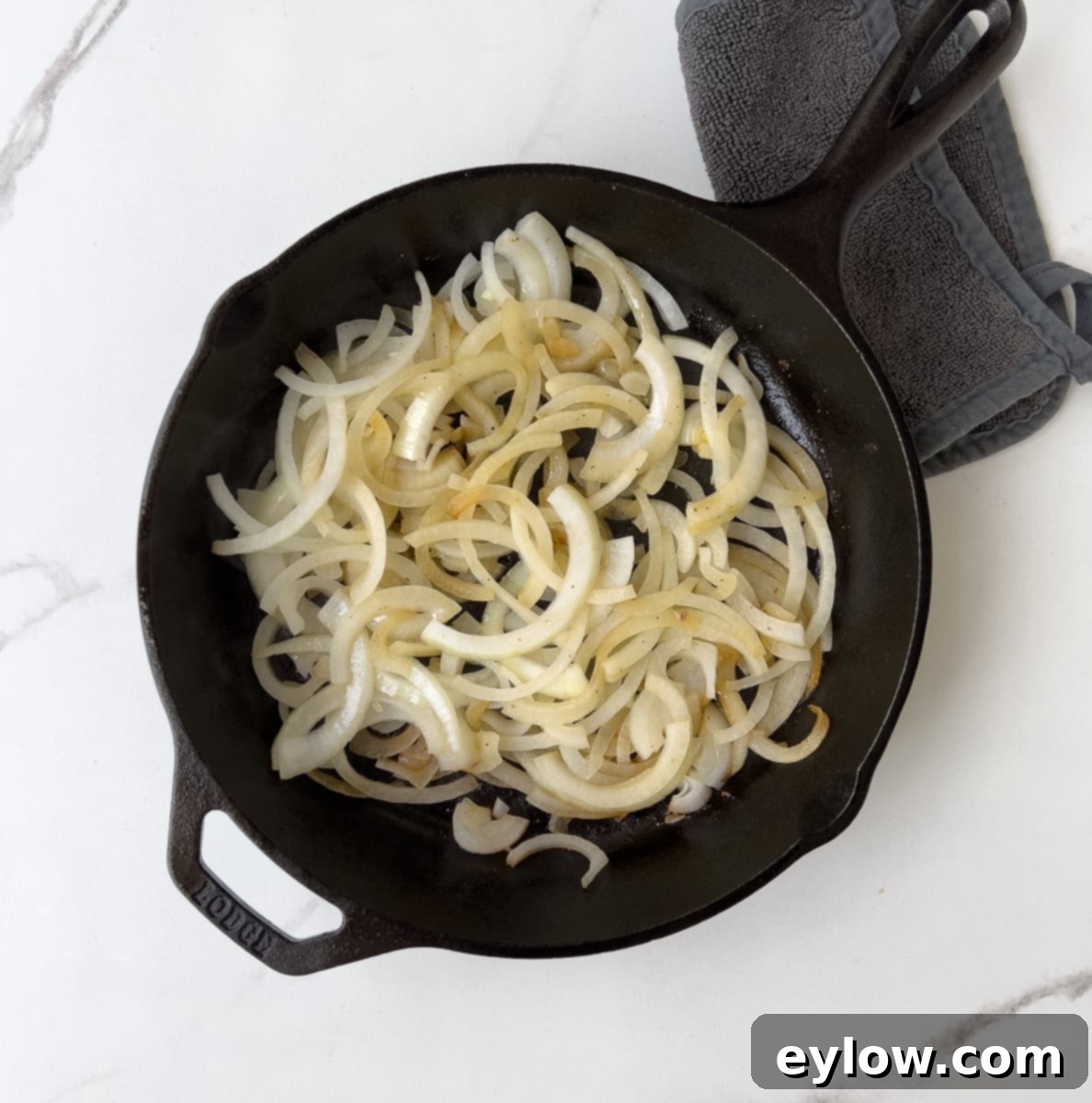 Creamy Sour Cream Pork Chops 6 Sliced onions beginning to cook in a cast iron pan with melted butter.