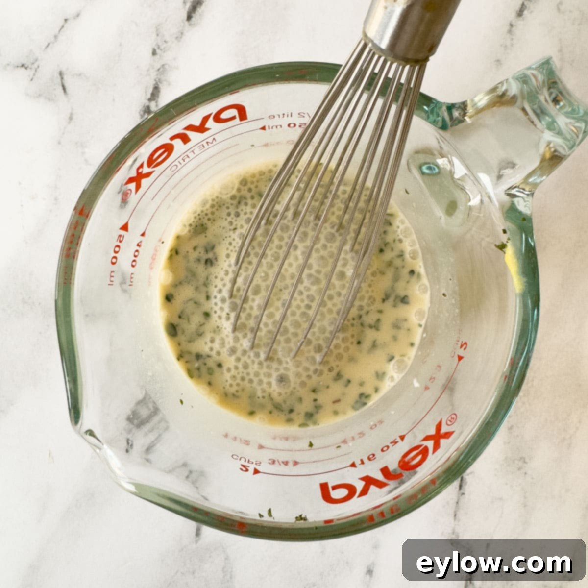 Creamy Sour Cream Pork Chops 9 Broth, creme fraiche, thyme, and Dijon mustard being whisked together in a glass measuring cup.