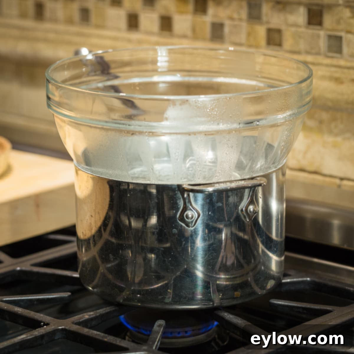 Showing a double boiler set up with a pot topped with a glass bowl on stove top.
