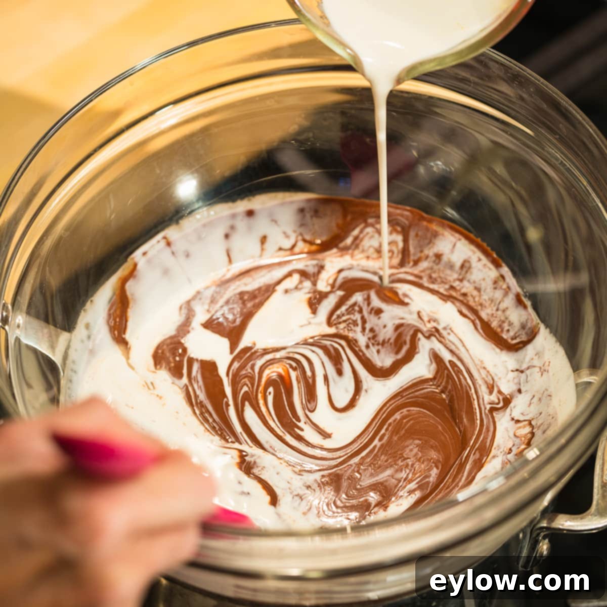 Making chocolate filling, pouring coconut milk into melted chocolate.