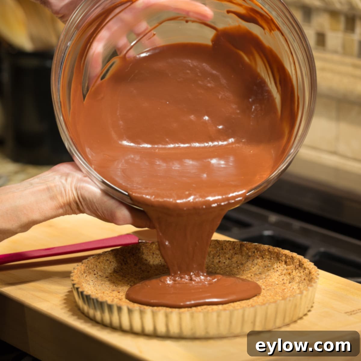 Pouring the liquid chocolate filling into a tart crust. 