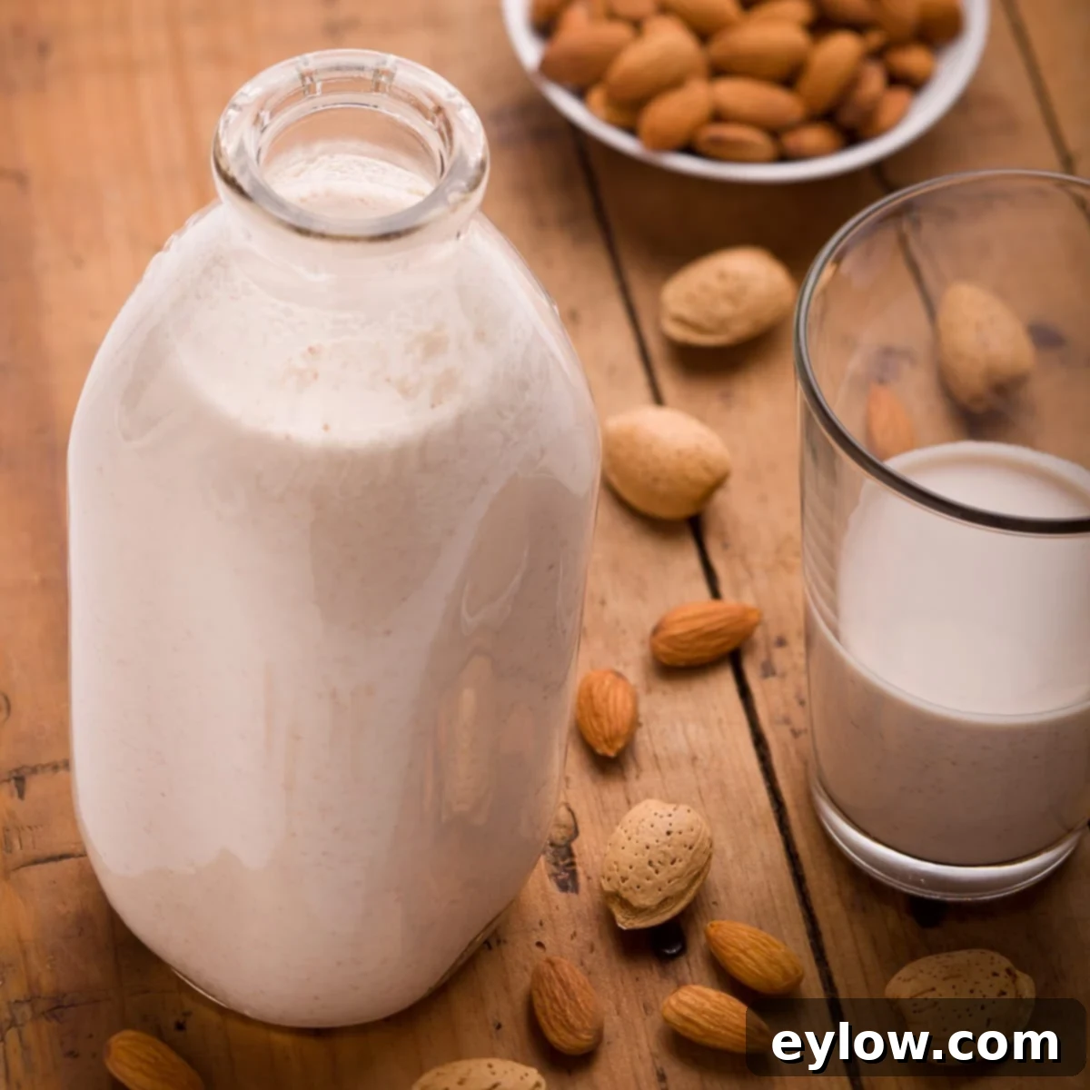 A glass dairy bottle of homemade almond milk with raw almonds on a wooden table, emphasizing freshness and natural ingredients.