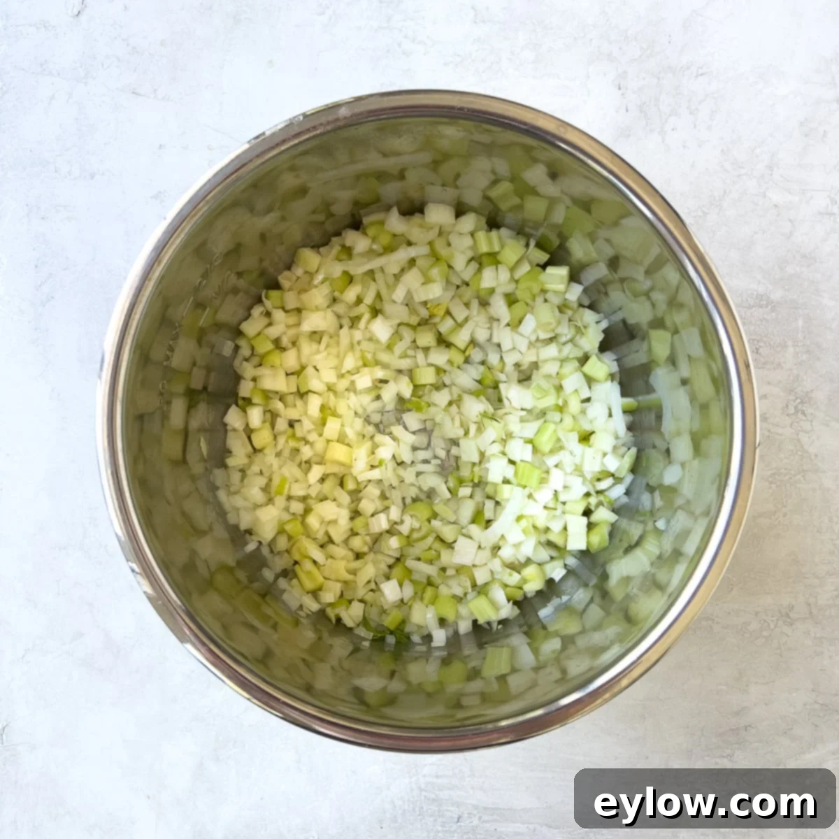 Sautéing diced onions, celery, and fennel in an Instant Pot with olive oil.