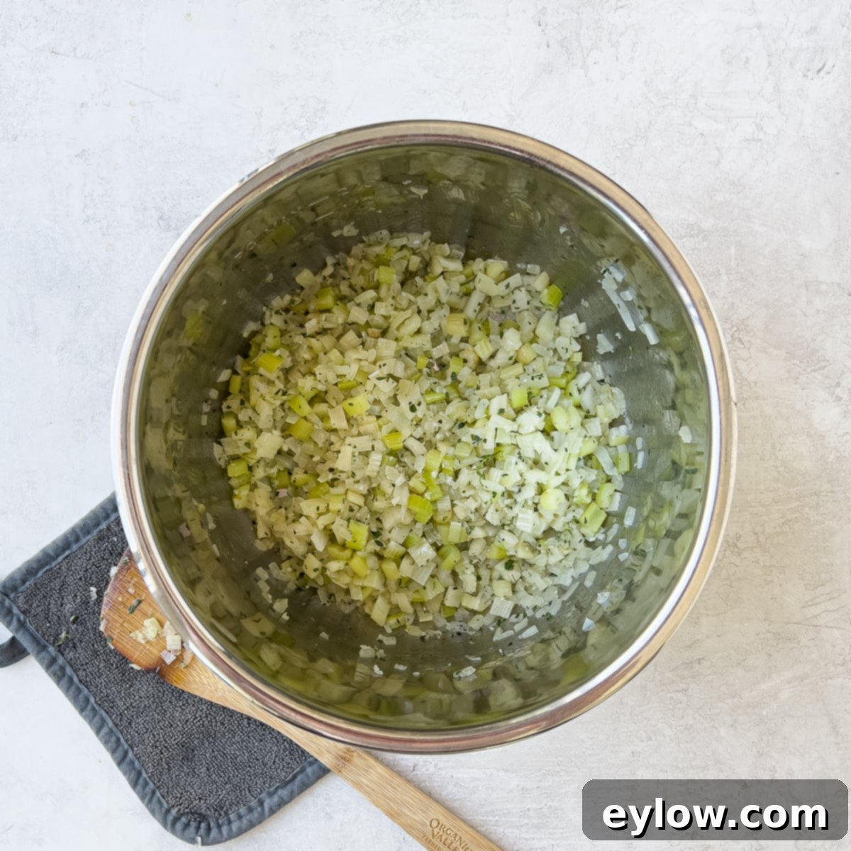 Sautéed vegetables in the Instant Pot, with thyme, bay leaf, and garlic added and being stirred.