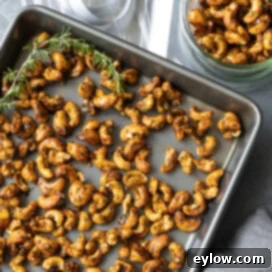 Sweet and spicy maple cashews. A close-up of a pile of golden-brown cashews seasoned with rosemary and spices.