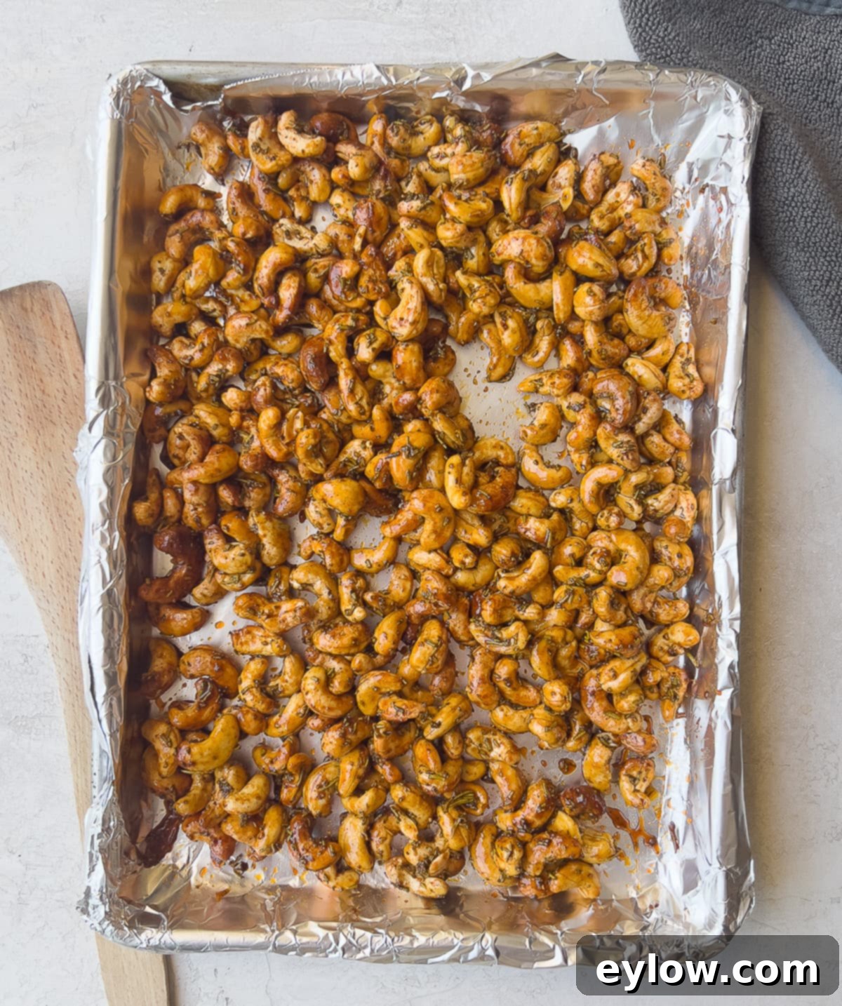 Maple Glazed Sweet and Spicy Cashews 6 Golden brown cashews finished roasting on baking sheet. Perfectly roasted maple cashews are spread on a non-stick foil-lined baking sheet, glistening and ready to cool.