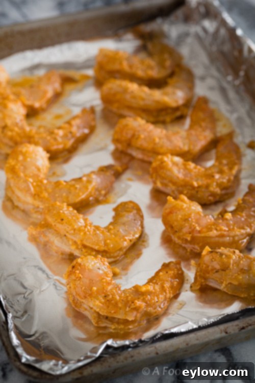 Zesty Lemon Garlic Baked Shrimp 3 Raw shrimp marinating in a flavorful sauce on a baking sheet