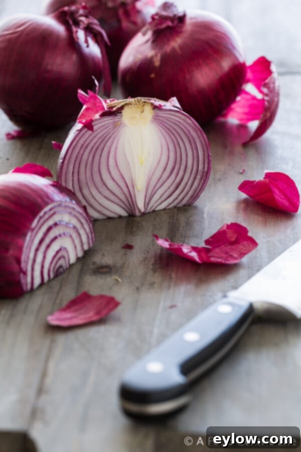 Close-up of thinly sliced red onions arranged on a cutting board, ready for roasting.
