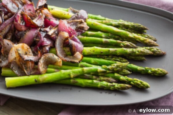 Balsamic and fresh thyme are added to the warm caramelized red onions in a white baking dish, ready to be tossed and served.
