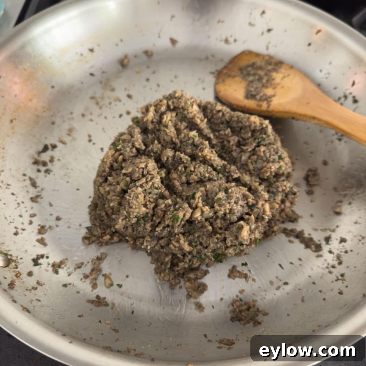 Finished mushroom duxelles, brown with green chopped herbs.