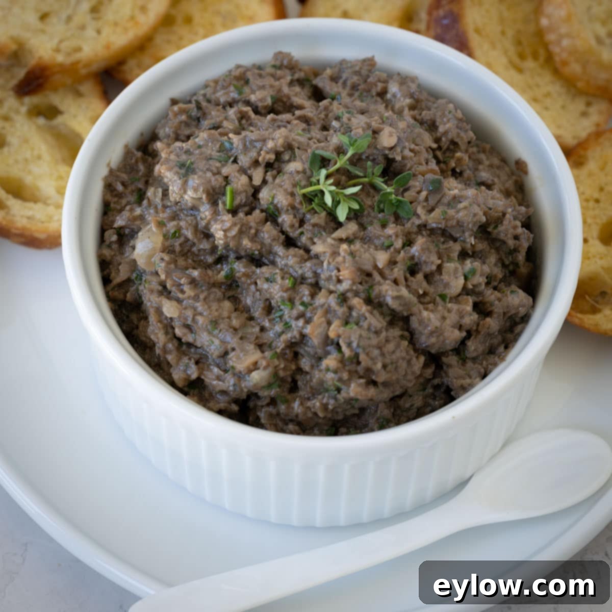 Closeup of mushroom pate in a white ramekin with a spoon.