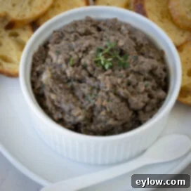 Closeup of mushroom pate in a white ramekin with a spoon.