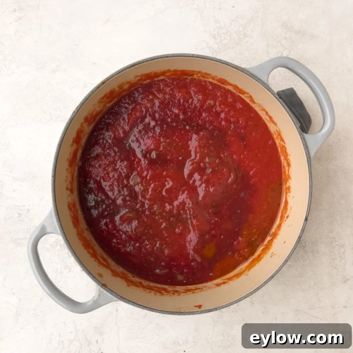 Tomato marinara simmering gently with red wine in a pot, demonstrating the final cooking stage. 