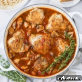 Effortless One Pan Italian Chicken Thighs 12 A round pan of golden chicken thighs in red sauce with rosemary on the side.