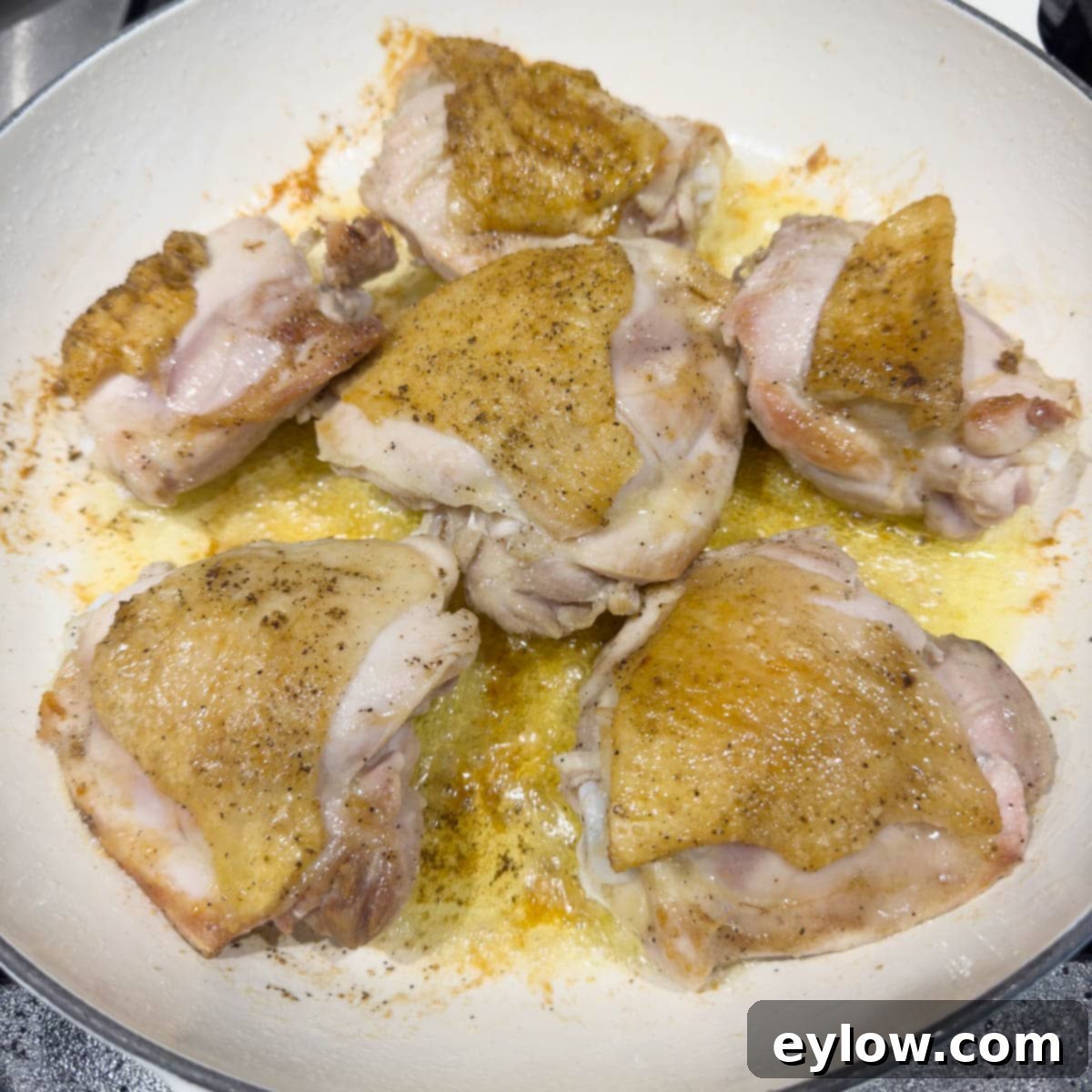 Effortless One Pan Italian Chicken Thighs 6 Crispy golden chicken thighs in a white pan ready for next step.