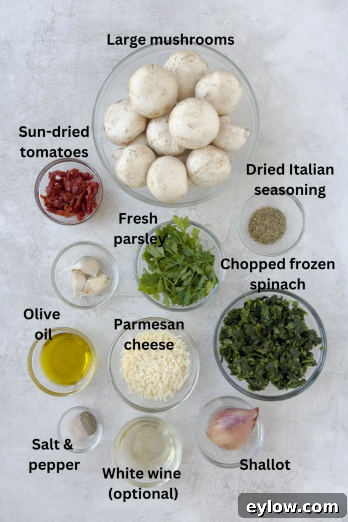 Ingredients for spinach stuffed mushrooms displayed in small prep bowls on a kitchen counter, ready for assembly.