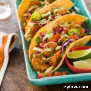 A plate of grilled shrimp tacos, showing the golden tortillas, colorful toppings, and perfectly cooked shrimp.