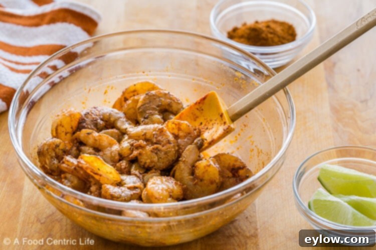 A bowl of raw shrimp marinating before grilling on a wooden cutting board.