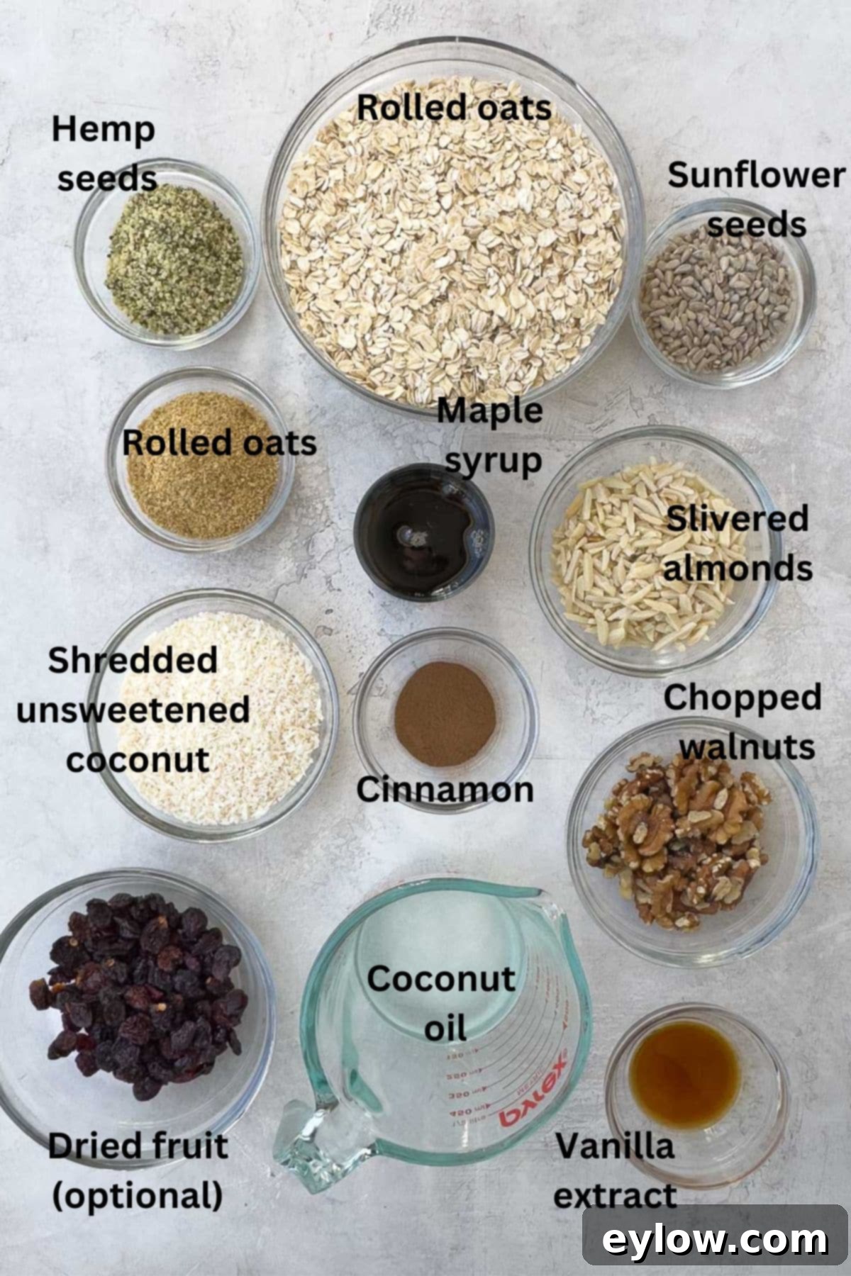 Bowls of healthy ingredients for homemade granola including oats, nuts, seeds, and spices, ready for mixing.