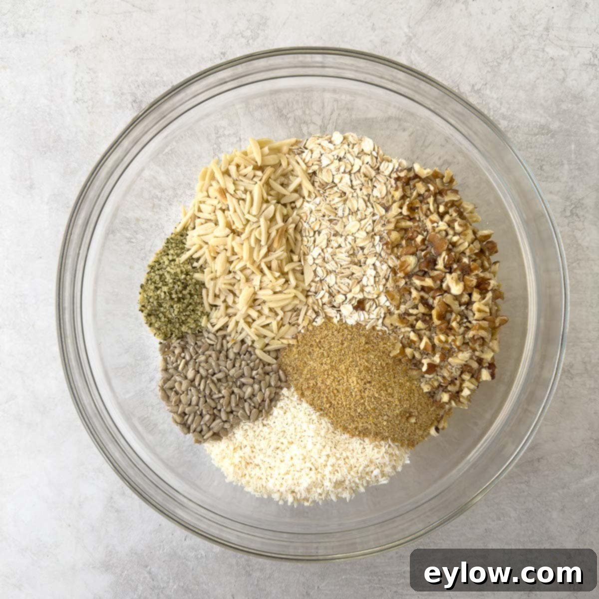 Dry ingredients for healthy homemade granola in a large glass mixing bowl.