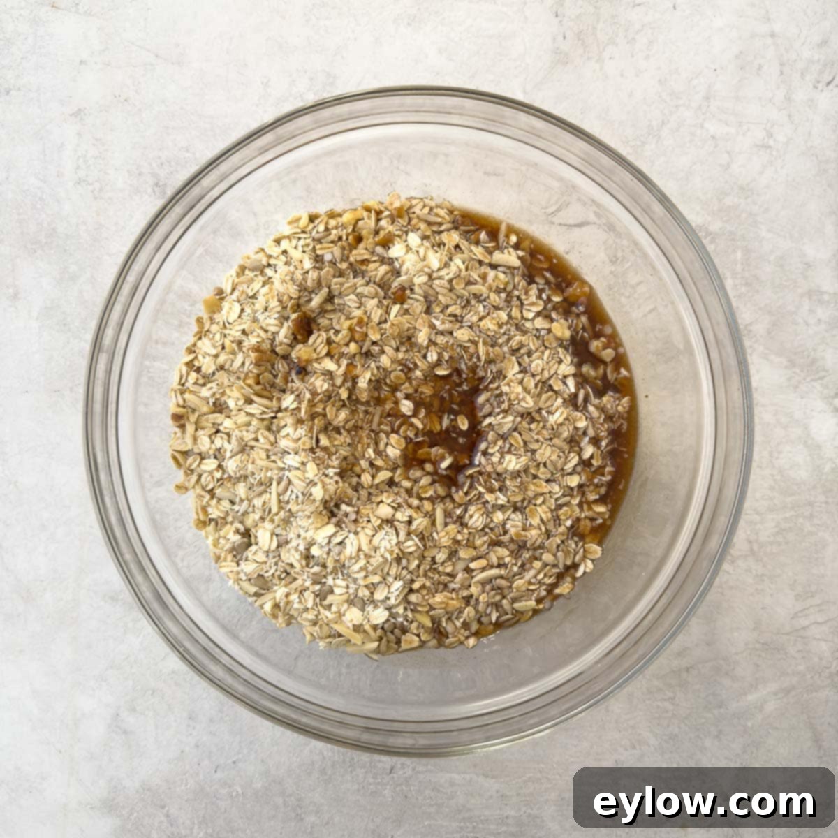 Mixing wet ingredients with dry ingredients in a large bowl to create the homemade granola mixture.