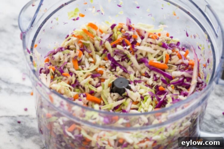 Creamy Apple Cider Crunch Slaw 4 A vibrant mix of green cabbage, shredded carrots, and purple cabbage, ready to be combined into a colorful broccoli slaw.