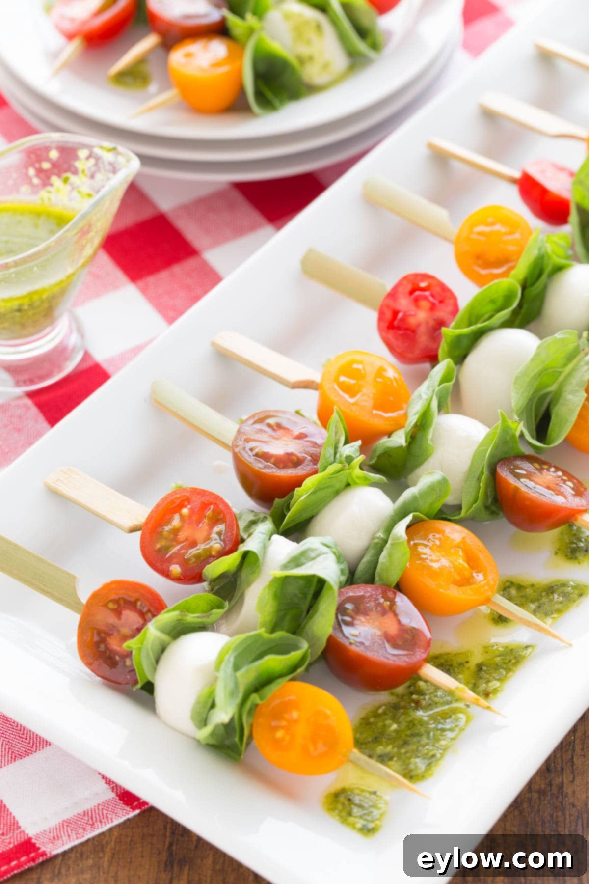 Quick Caprese Bites with Homemade Basil Vinaigrette 2 Colorful caprese appetizer skewers with cherry tomatoes, mozzarella balls, and basil leaves on a tray.