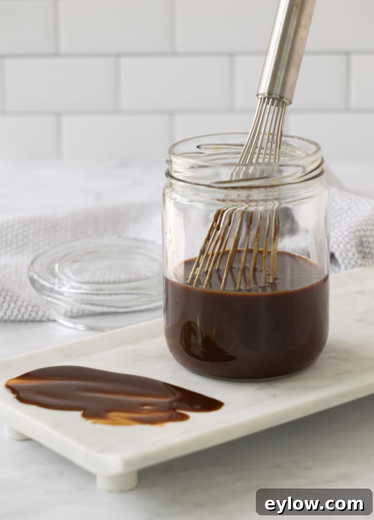 Homemade Gluten-Free Hoisin 2 A jar of rich brown hoisin sauce in a jar with a silver whisk.