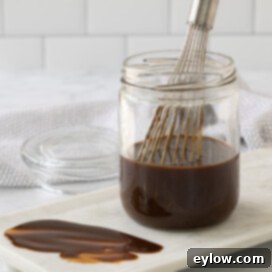 Homemade Gluten-Free Hoisin 8 A glass jar with rich brown hoisin sauce and a whisk for mixing.