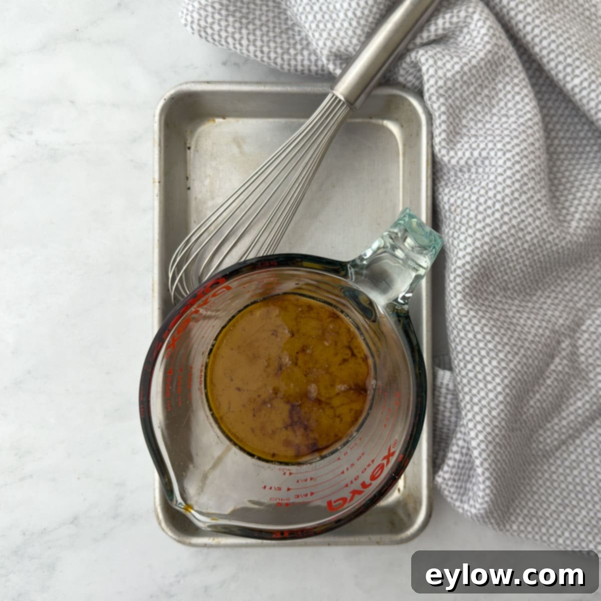 Homemade Gluten-Free Hoisin 4 Ingredients for sauce in a Pyrex glass measuring cup with a whisk for mixing.