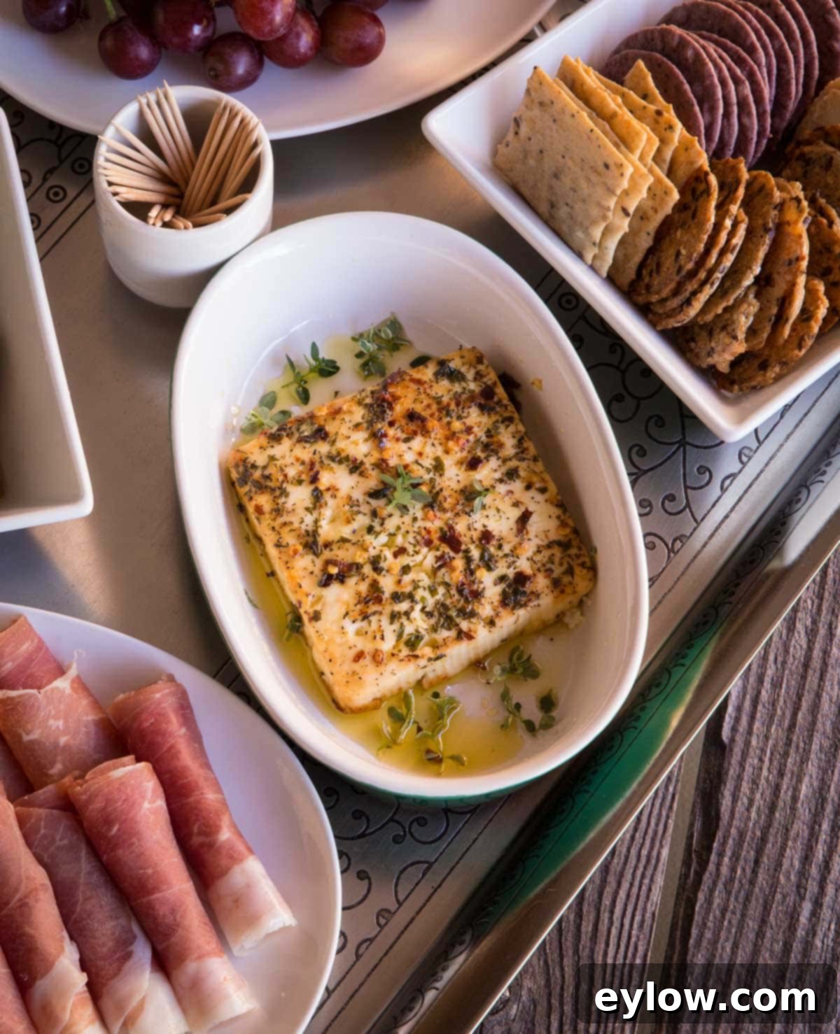 Mediterranean Mezze: Warm Feta & Fresh Bites 2 Baked feta cheese as part of a vibrant mezze platter of Mediterranean appetizers, featuring olives, grapes, and crackers.