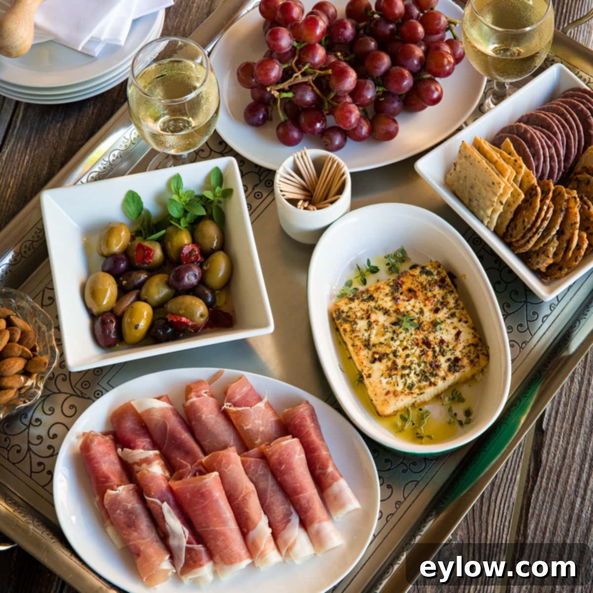 Mediterranean Mezze: Warm Feta & Fresh Bites 3 Mediterranean appetizer tray called a mezze platter with baked feta cheese, prosciutto, olives, grapes, and crackers.