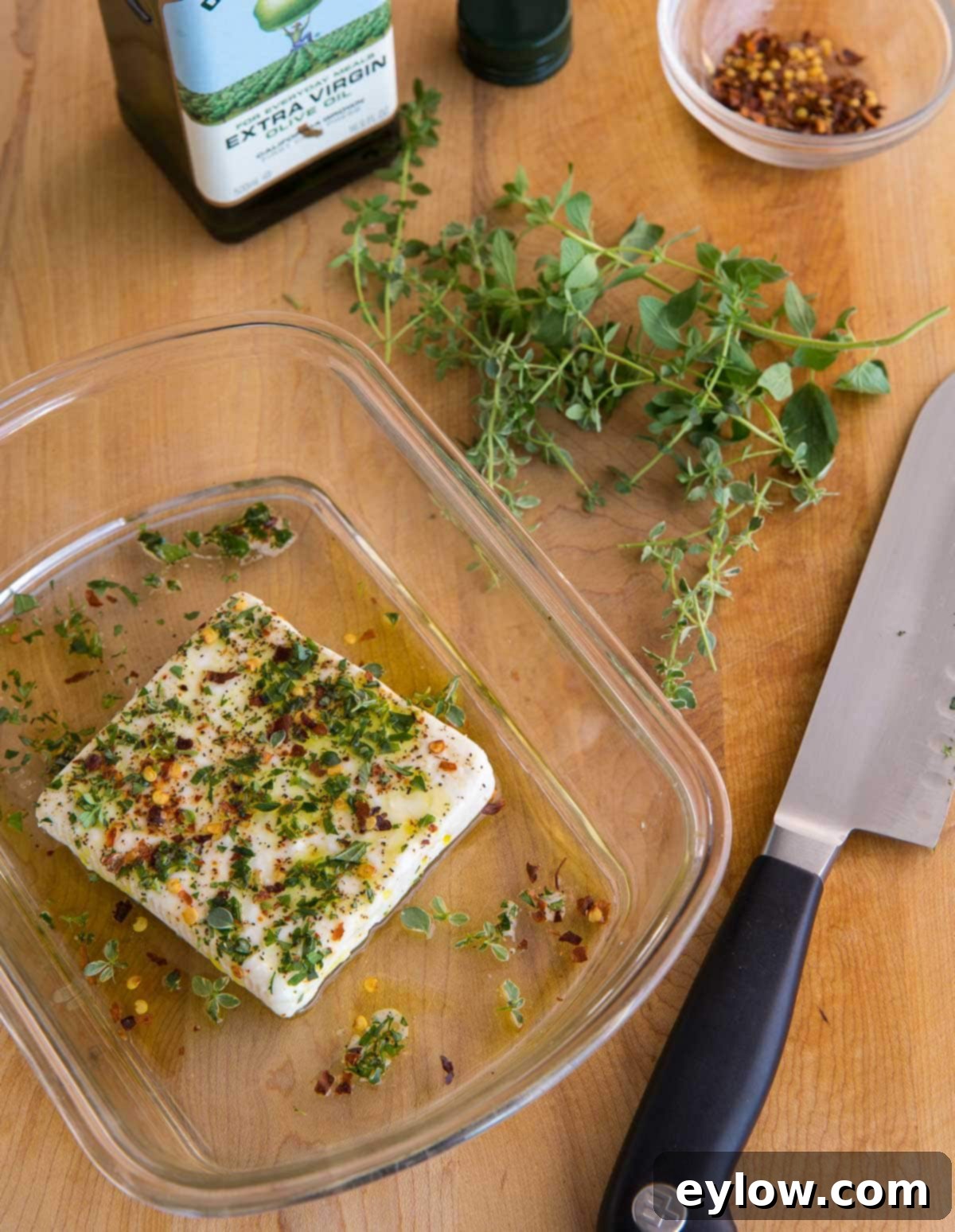 Mediterranean Mezze: Warm Feta & Fresh Bites 4 A block of feta cheese in a baking dish with olive oil and herbs, ready to bake before becoming part of a mezze platter.