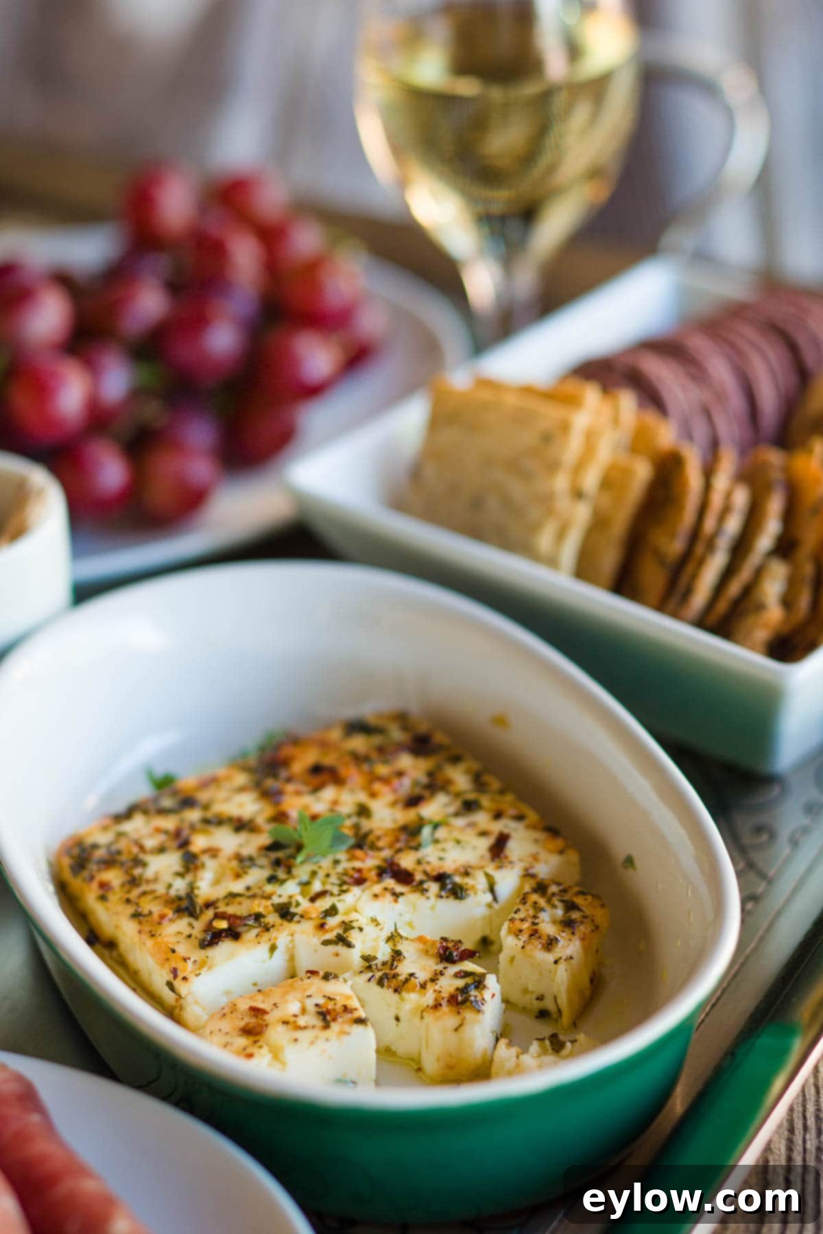 Mediterranean Mezze: Warm Feta & Fresh Bites 5 Close up of warm baked feta cheese on a mezze platter with green grapes and assorted crackers, ready to serve.