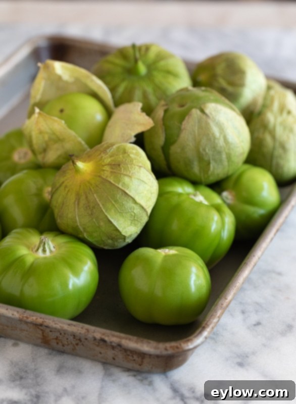 A tray of raw green tomatillos, some with papery husks. 