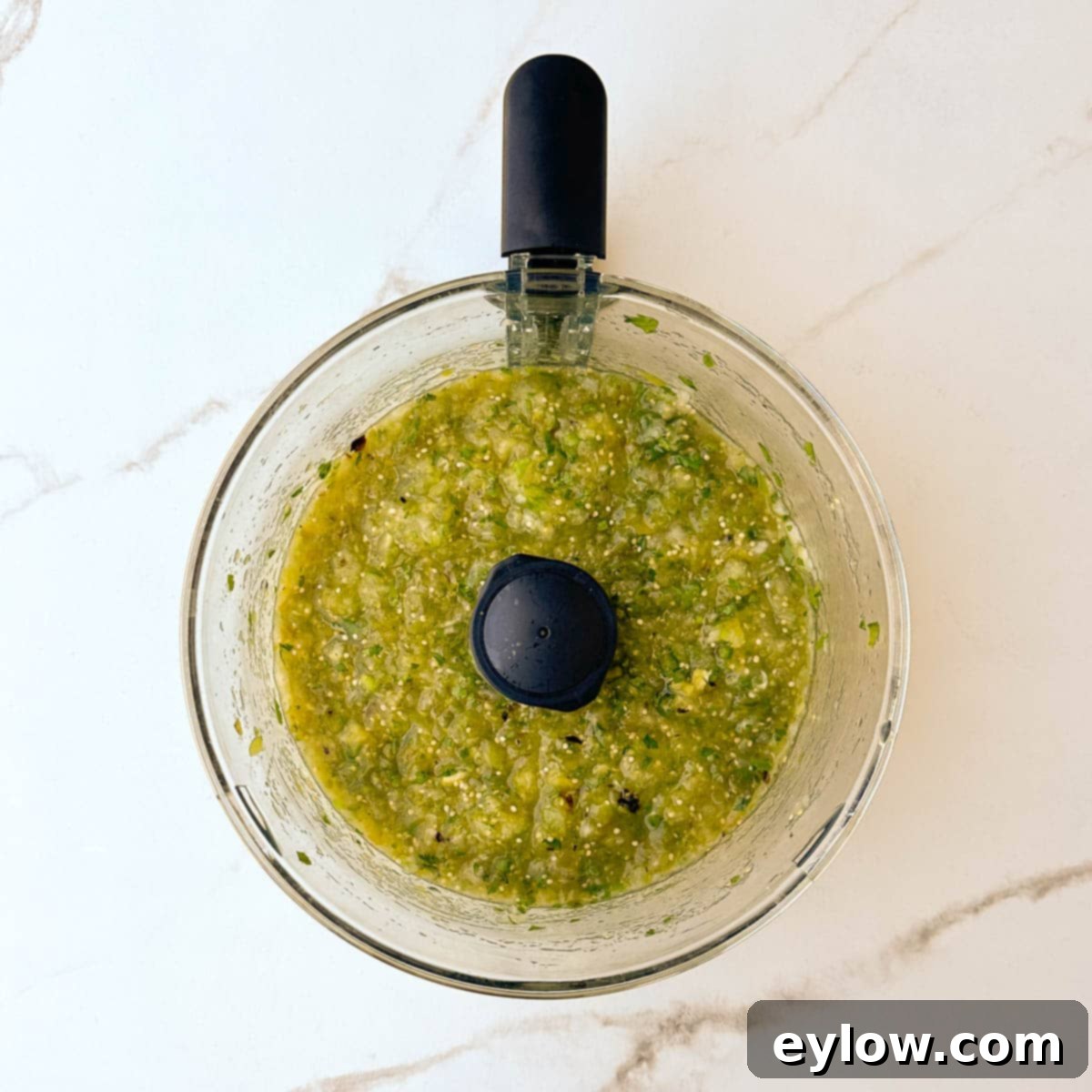 Pureed salsa verde, still a bit chunky, ready to serve, in a food processor.