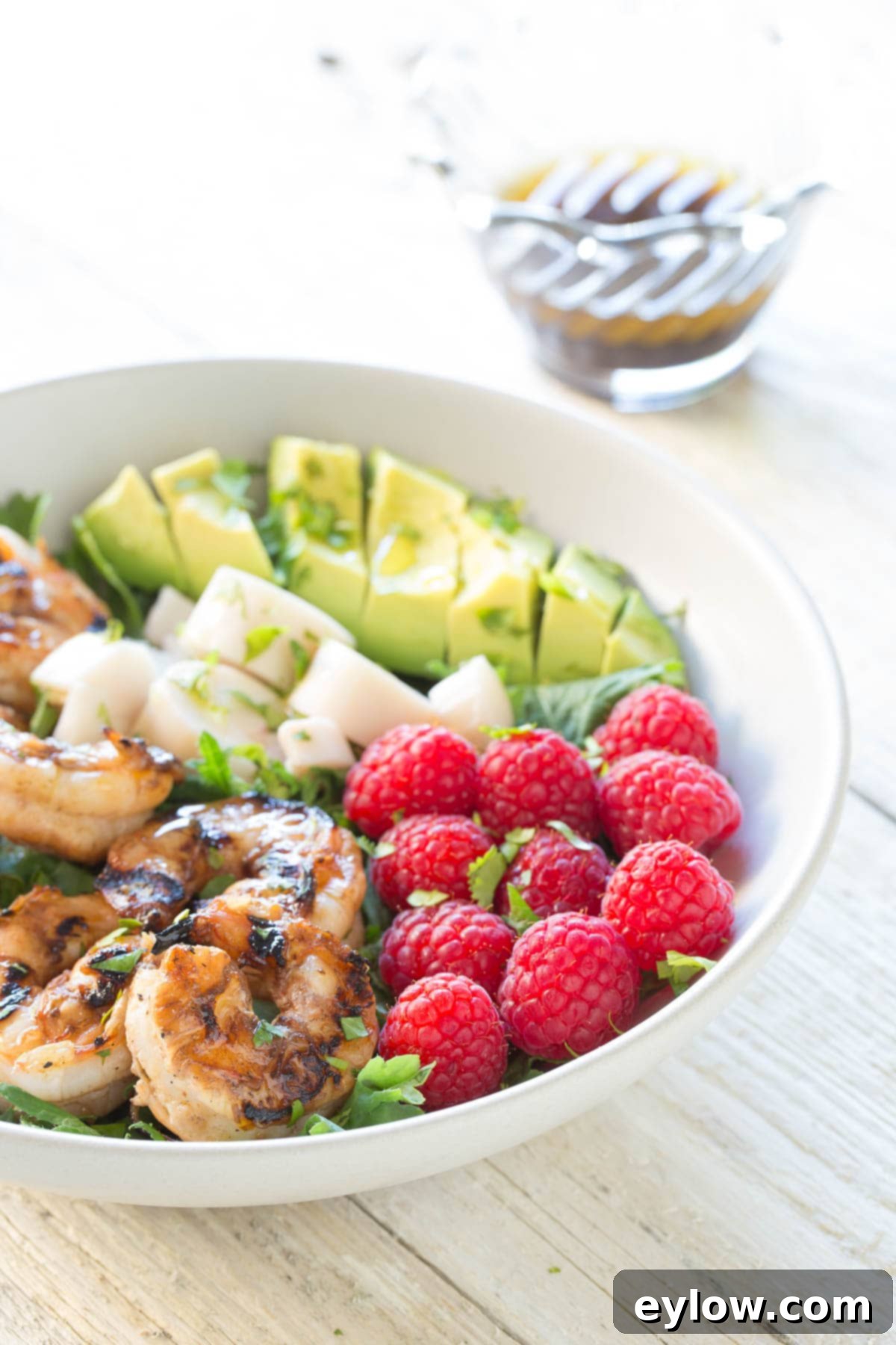 Grilled shrimp, heart of palm, raspberries, and avocado in a bowl for a salad.